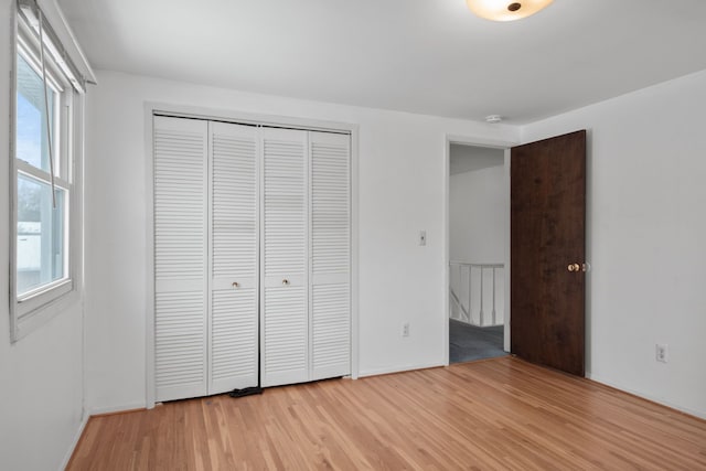 unfurnished bedroom featuring multiple windows, a closet, and light hardwood / wood-style flooring