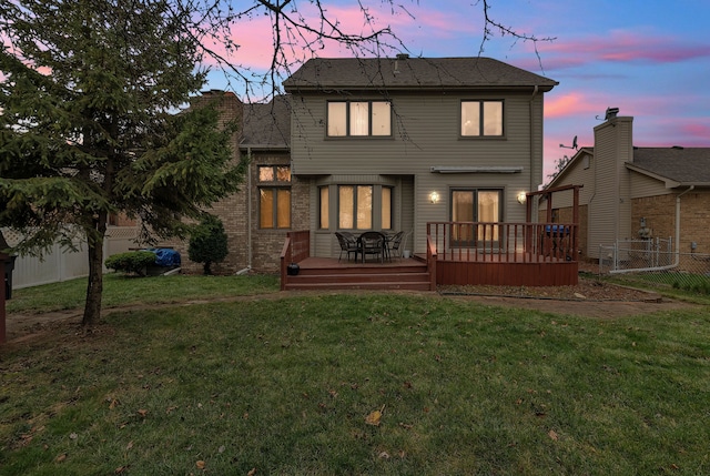 back house at dusk with a wooden deck and a yard