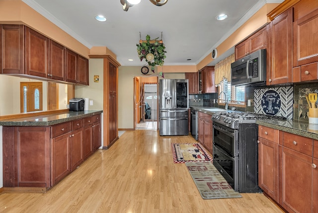 kitchen featuring sink, tasteful backsplash, light wood-type flooring, ornamental molding, and appliances with stainless steel finishes