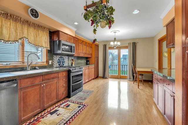 kitchen with sink, tasteful backsplash, light wood-type flooring, appliances with stainless steel finishes, and pendant lighting