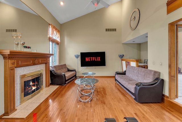 living room featuring a fireplace, high vaulted ceiling, and light wood-type flooring