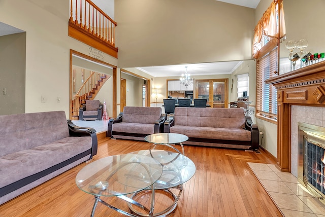 living room with a towering ceiling, a fireplace, light hardwood / wood-style floors, and a chandelier