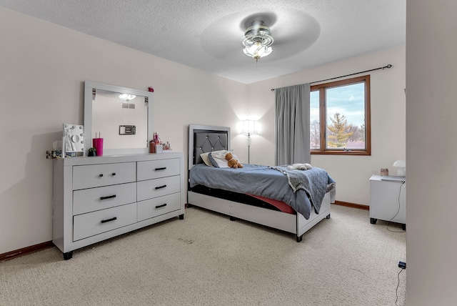 bedroom with ceiling fan, light colored carpet, and a textured ceiling