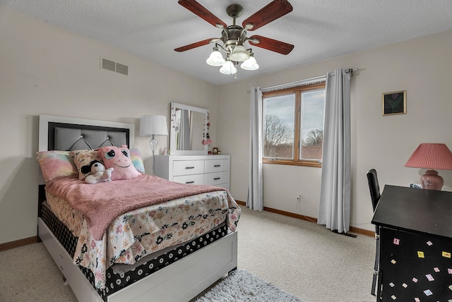 bedroom with ceiling fan, light colored carpet, and a textured ceiling