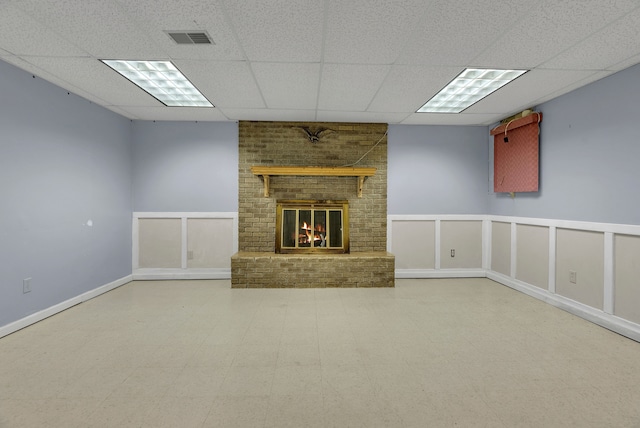 unfurnished living room featuring a brick fireplace and a drop ceiling