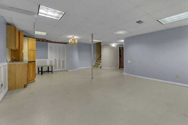 basement featuring a paneled ceiling and sink