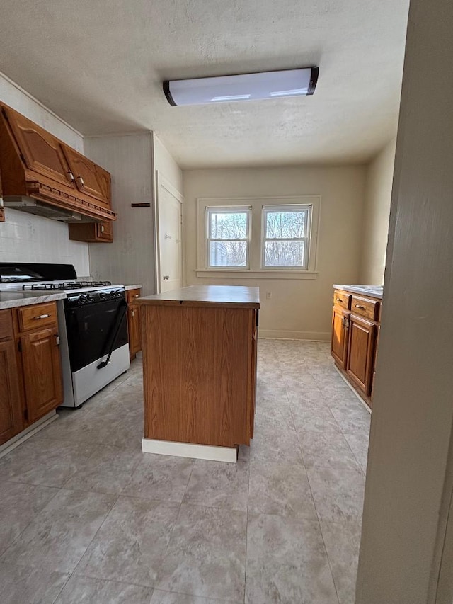 kitchen featuring premium range hood, tasteful backsplash, a center island, a textured ceiling, and gas range oven