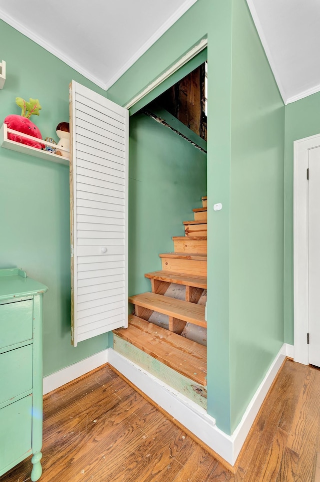 stairs featuring baseboards, ornamental molding, and wood finished floors