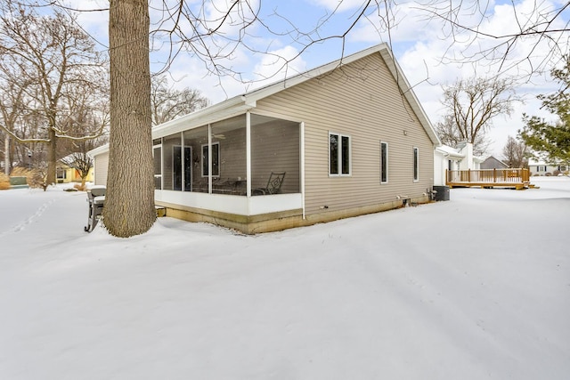 snow covered property with a sunroom and central air condition unit