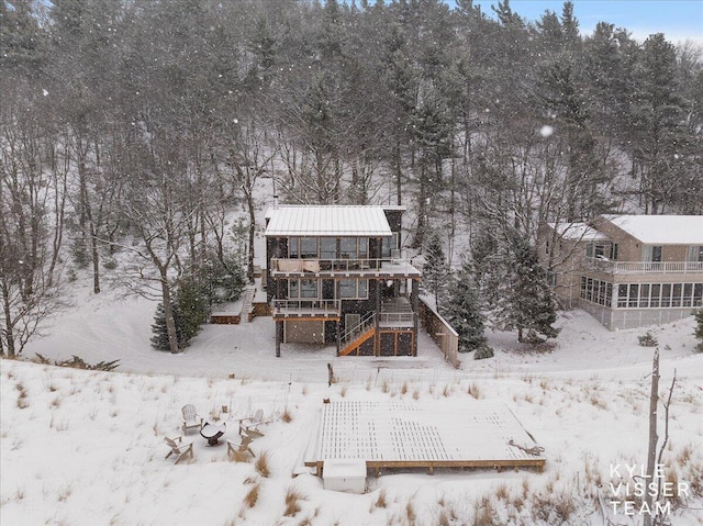 snow covered back of property featuring a wooden deck