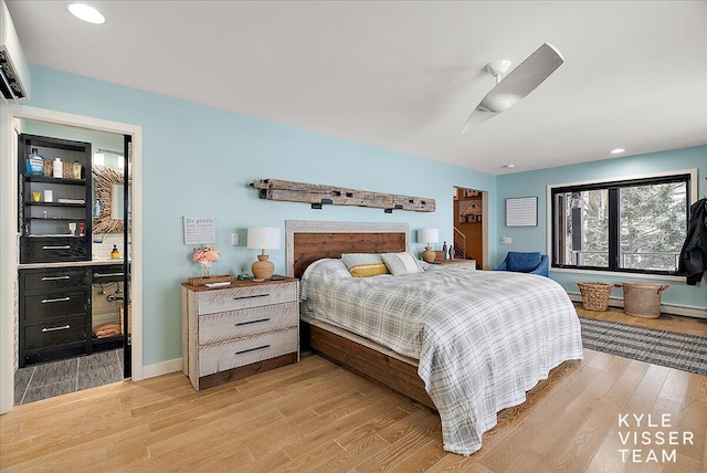 bedroom with ceiling fan, an AC wall unit, and light wood-type flooring