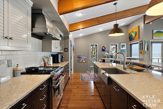 kitchen featuring pendant lighting, sink, high end stainless steel range, light stone countertops, and wall chimney exhaust hood