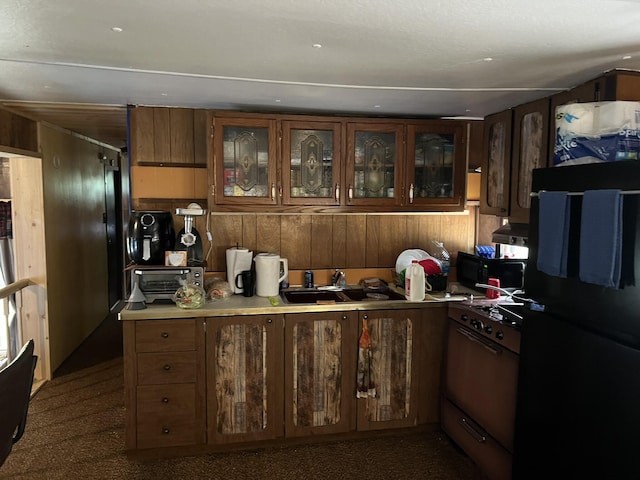 kitchen with wall oven, sink, refrigerator, and wood walls