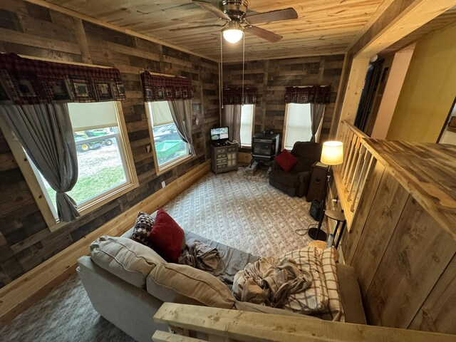 8210 N Johnson Rd, Irons, MI 49644 - carpeted living area with wooden walls, a wood stove, wooden ceiling, and a ceiling fan