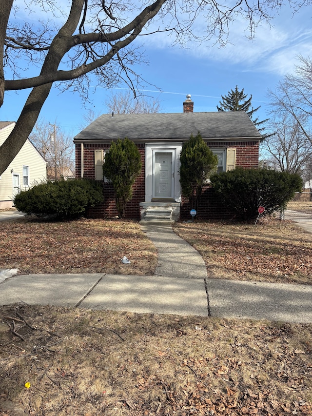 bungalow-style house featuring brick siding and a chimney