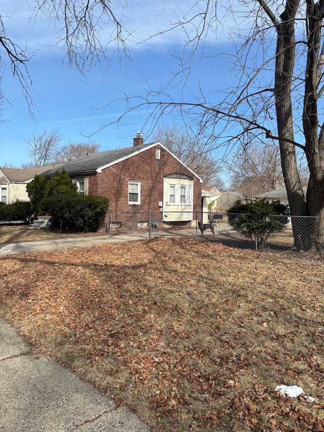 view of home's exterior featuring brick siding, a chimney, and a fenced front yard