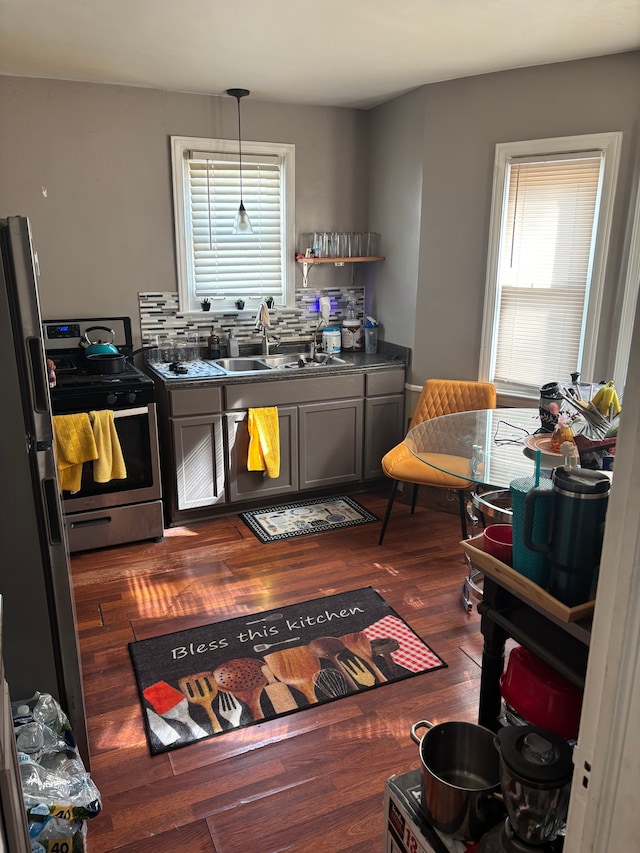 19331 Kingsville St, Harper Woods, MI 48225 - kitchen featuring a sink, dark countertops, dark wood-style floors, appliances with stainless steel finishes, and hanging light fixtures