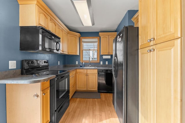 kitchen featuring a sink, light wood-style floors, light brown cabinetry, black appliances, and dark countertops