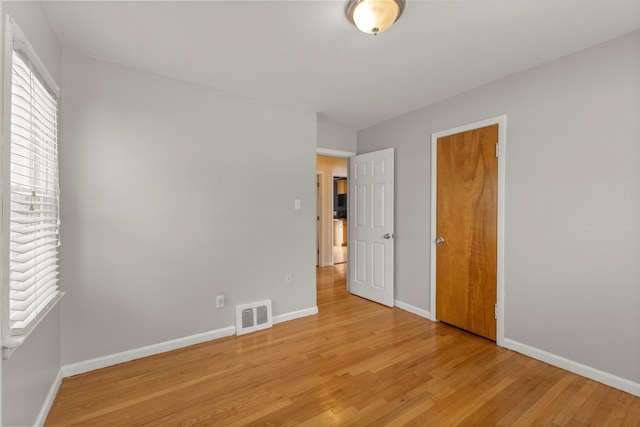 unfurnished bedroom with light wood finished floors, visible vents, and baseboards