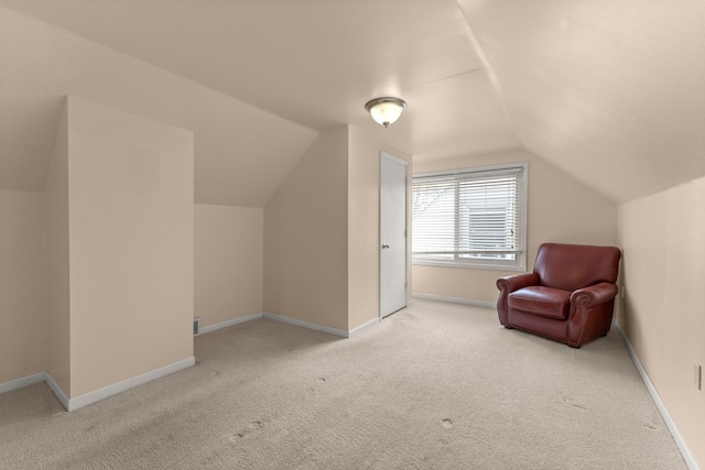 living area with lofted ceiling, light carpet, and baseboards