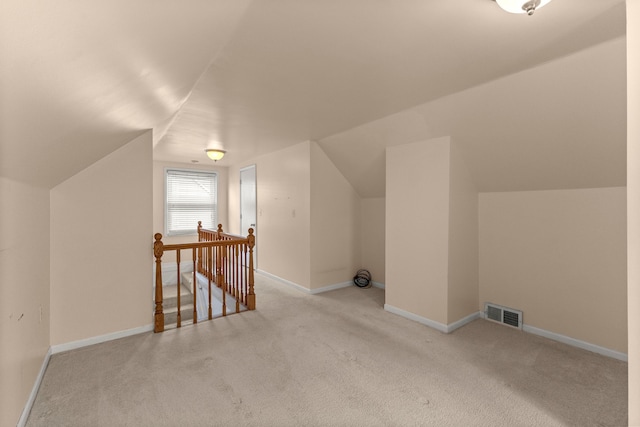 additional living space featuring lofted ceiling, visible vents, baseboards, and light colored carpet