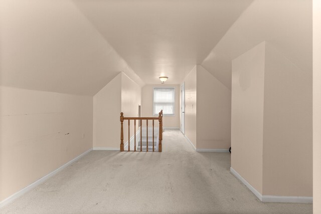 bonus room featuring lofted ceiling, light carpet, and baseboards