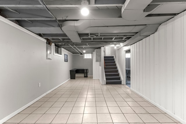 basement featuring stairway, light tile patterned flooring, and baseboards