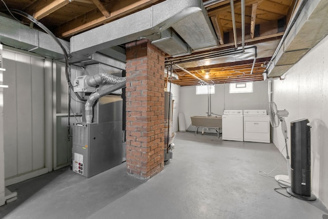 below grade area featuring water heater, a sink, washer and clothes dryer, and heating unit