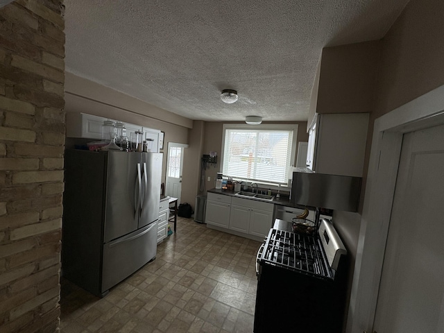 kitchen featuring stainless steel appliances, white cabinetry, sink, and a textured ceiling