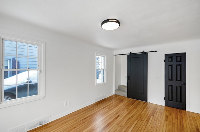 unfurnished bedroom with wood-type flooring and a barn door