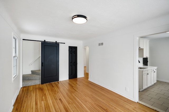 unfurnished bedroom with light hardwood / wood-style flooring and a barn door