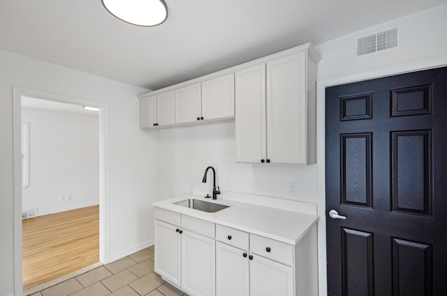 kitchen with light tile patterned floors, sink, and white cabinetry