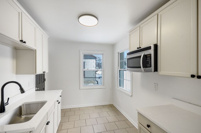 kitchen featuring sink, white cabinetry, and light tile patterned flooring