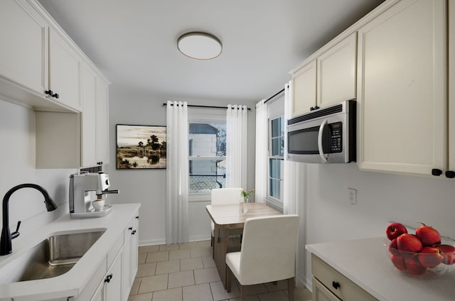 kitchen featuring sink, white cabinetry, and light tile patterned floors