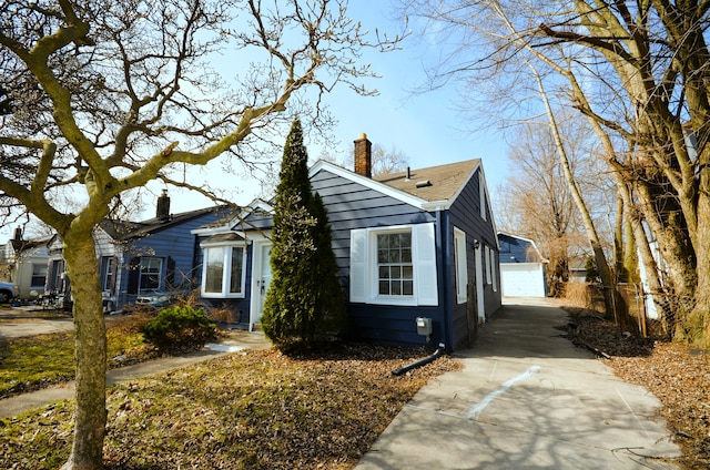 bungalow-style home with an outbuilding, a chimney, and a detached garage