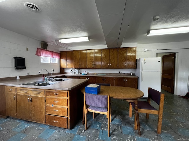 kitchen with kitchen peninsula, sink, and white fridge