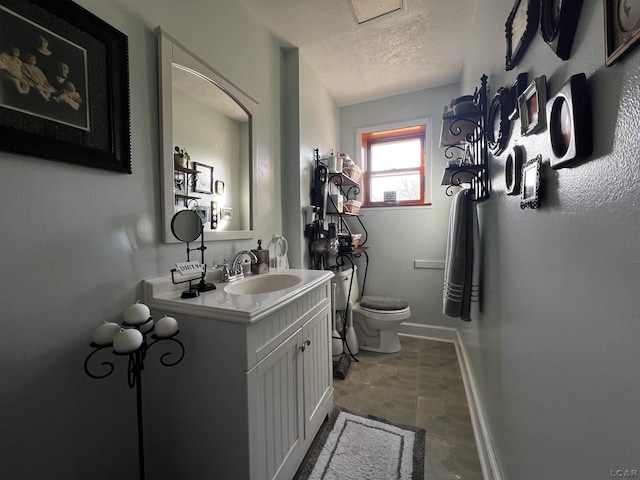 bathroom featuring vanity, toilet, and a textured ceiling