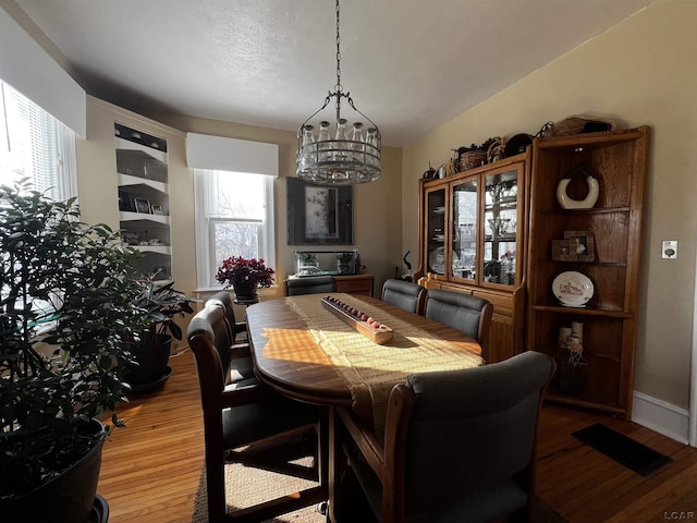 dining area with hardwood / wood-style flooring and a notable chandelier