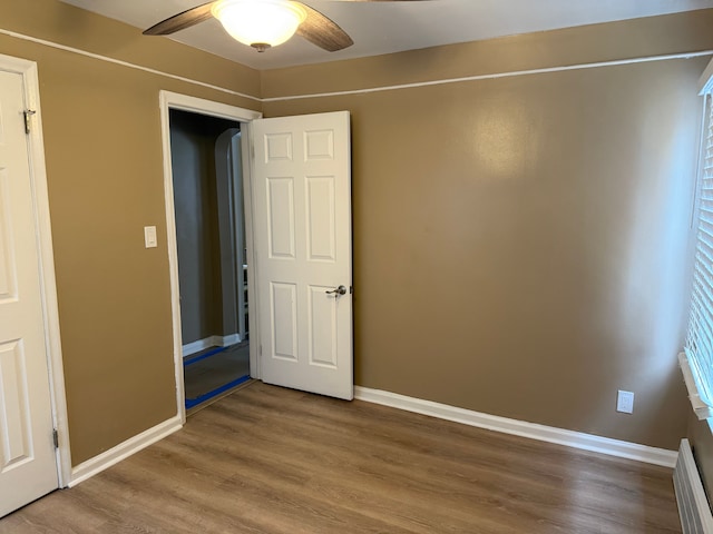 unfurnished bedroom with ceiling fan, baseboards, and wood finished floors