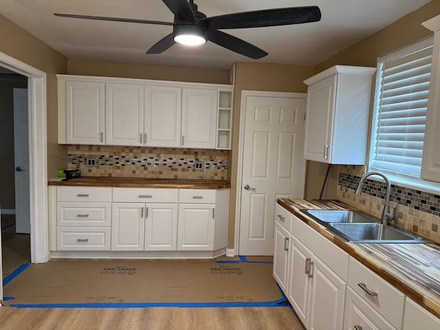 kitchen featuring light wood-style flooring, white cabinetry, backsplash, and a sink