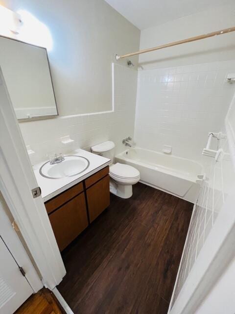 full bathroom featuring tile walls, vanity, wood-type flooring, tiled shower / bath, and toilet