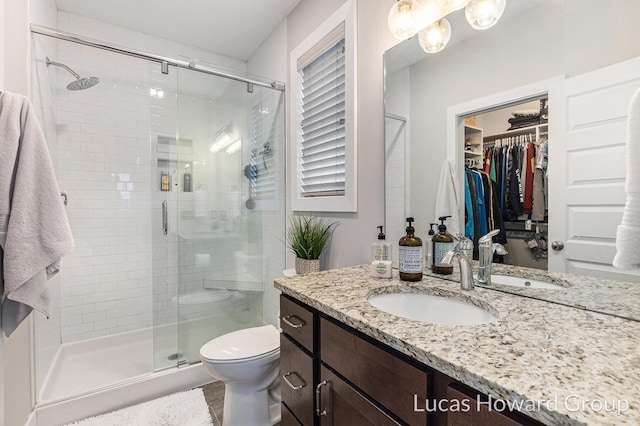 bathroom featuring vanity, toilet, and a shower with shower door