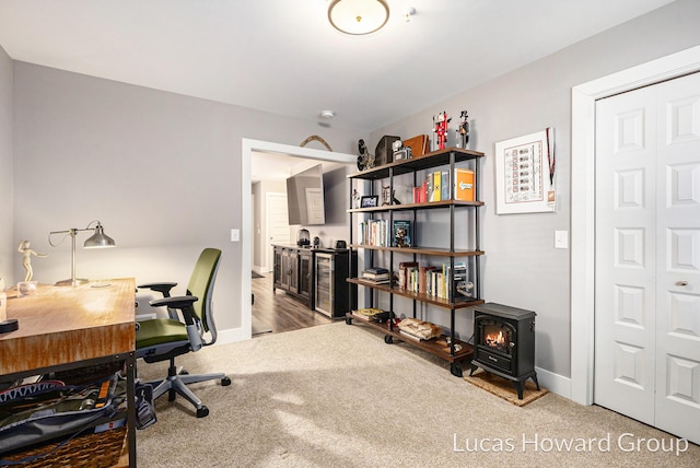 carpeted office space featuring a wood stove