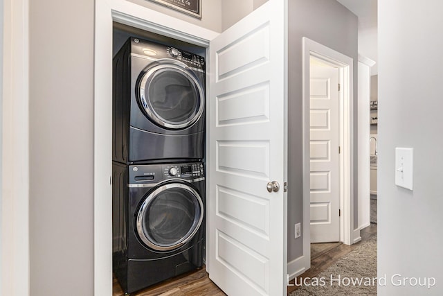 laundry room featuring hardwood / wood-style floors and stacked washer / dryer