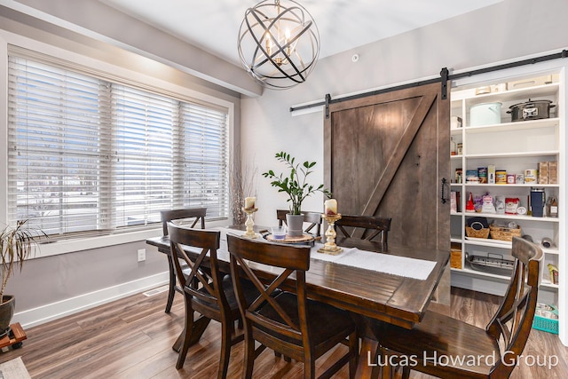 dining space with hardwood / wood-style flooring, a barn door, and a chandelier