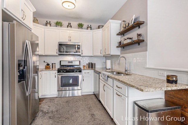 kitchen featuring sink, backsplash, stainless steel appliances, light stone countertops, and white cabinets