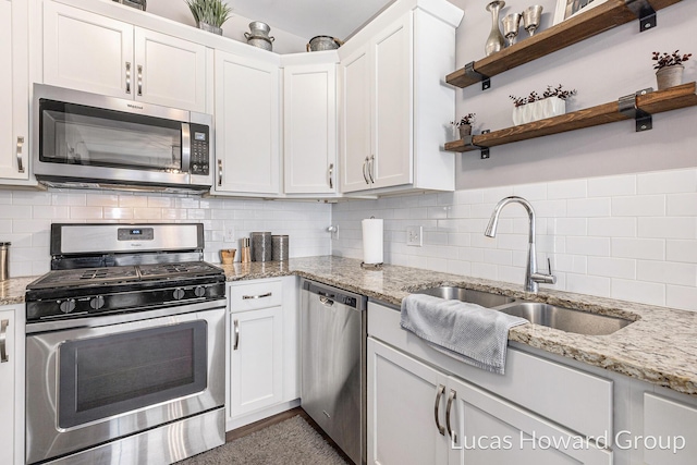 kitchen featuring appliances with stainless steel finishes, sink, white cabinets, backsplash, and light stone counters