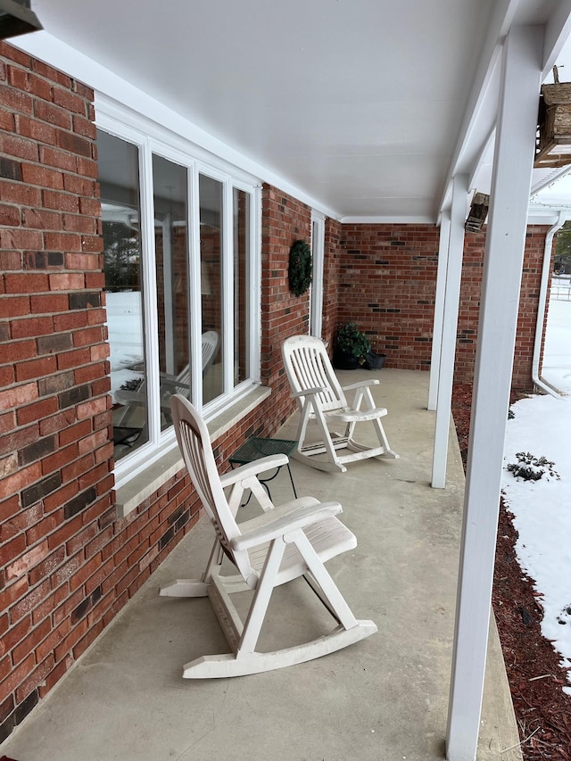 snow covered patio featuring covered porch