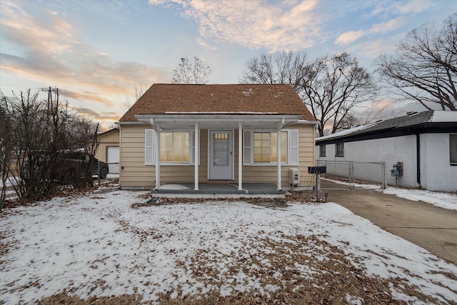 snow covered rear of property featuring covered porch