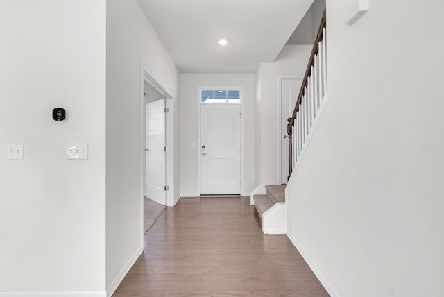 foyer entrance featuring stairs, wood finished floors, and baseboards